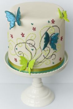 a white cake with blue and green butterflies on it