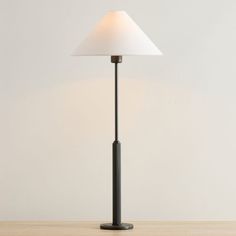 a lamp that is sitting on top of a wooden table next to a white wall