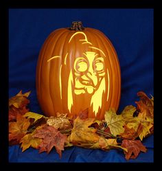 a carved pumpkin with an image of a demon on it and some leaves around it