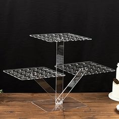 three tiered clear cake stand with white frosting on the bottom and black design