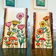 two pieces of wood with flowers painted on them sitting on a table next to each other