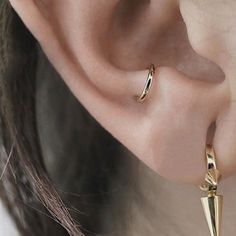 a close up of a person's ear wearing gold earrings