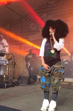 a woman standing on top of a stage holding a microphone in front of her face