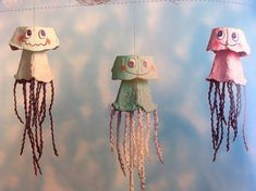 three paper jellys hanging from strings in the shape of octopuses with faces on them