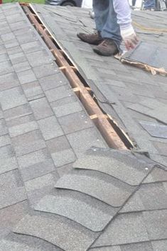 two men working on the roof of a house that has been gutted with shingles