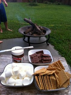 marshmallows, graham crackers and hot chocolate are on the picnic table