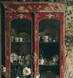 an old china cabinet with flowers and dishes