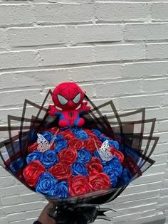 a person holding a bouquet of roses in front of a brick wall with a spiderman on it