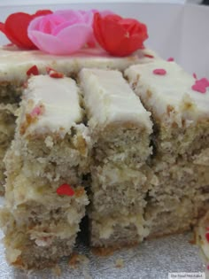 a close up of a piece of cake with white frosting and red sprinkles