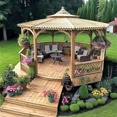 a wooden gazebo sitting in the middle of a lush green yard with flowers and potted plants