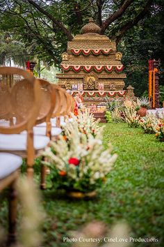 an outdoor ceremony set up with chairs and flowers on the grass in front of it