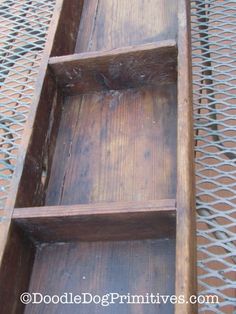 an old wooden shelf sitting on top of a metal grate