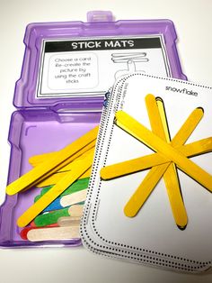 a purple box with yellow sticks sticking out of it next to a plastic container filled with colored pencils