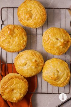 four pies sitting on top of a cooling rack next to a fork and knife