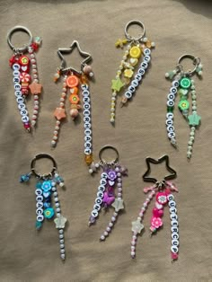 six keychains with beads and charms on them sitting on a cloth covered surface