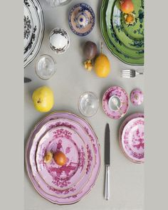 the table is set with plates, silverware and fruit