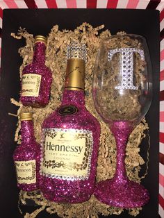 a bottle of wine and two glasses in a box with pink sequins on it