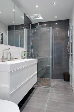 a bathroom with a walk in shower next to a white toilet and sink under lights