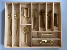 an open drawer with utensils, spoons and forks in it on a blue wall