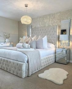 a large white bed sitting in a bedroom next to a window with a chandelier