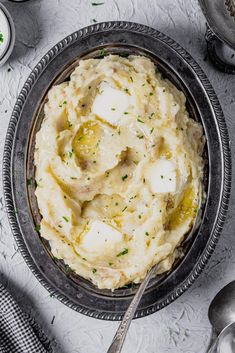 mashed potatoes with butter and parsley in a metal bowl on a white table