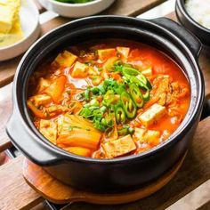 a bowl of soup with tofu and green onions