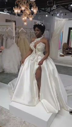 a woman in a wedding dress sitting on a white platform with her legs crossed and wearing a tiara