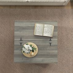 an overhead view of a coffee table with two open books and a vase filled with flowers