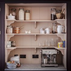 the shelves in this kitchen are filled with dishes and coffee maker, cups, and other items