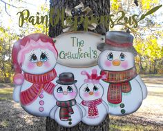 a group of snowmen hanging from the side of a tree in front of a sign