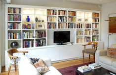 a living room filled with furniture and a flat screen tv on top of a book shelf