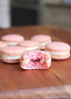 some pink and white cookies are on a wooden table