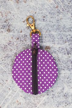 a purple and white polka dot zippered coin purse hanging on a metal key chain