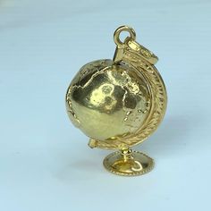 an antique gold globe on a stand with a chain around the neck and bottom part