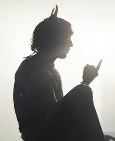 the silhouette of a man with horns on his head holding a cell phone in his hand