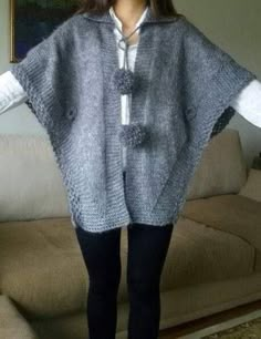 a woman standing in front of a couch wearing a sweater