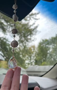 a hand holding a glass bead hanging from a car dashboard