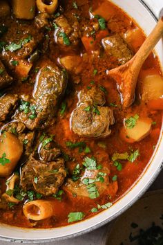 a bowl of stew with meat, potatoes and parsley