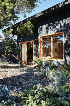 a house that has some plants in front of it and trees around the outside area