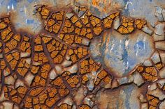 an old rusted metal surface with orange and blue paint