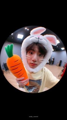 a girl in bunny ears holding a carrot
