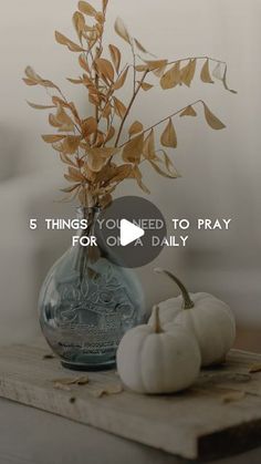 there is a vase with some flowers in it and two pumpkins on the table