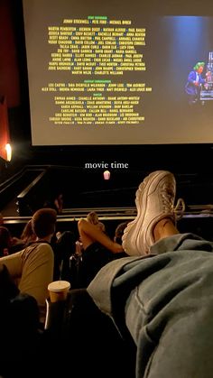 people sitting in front of a projector screen watching movies on the floor with their feet up