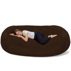 a woman laying on top of a brown bean bag chair