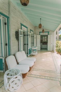 there are white couches and chairs on the front porch with blue trim around them