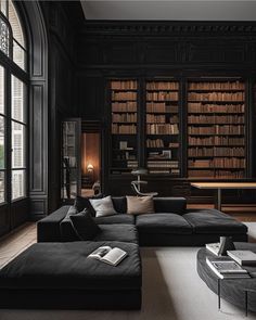 a living room filled with black furniture and lots of bookshelves on the walls