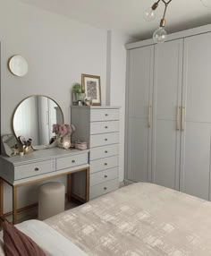 a bedroom with a dresser, mirror and dressing table in the corner next to it