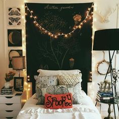 a white bed topped with lots of pillows next to a wall covered in string lights