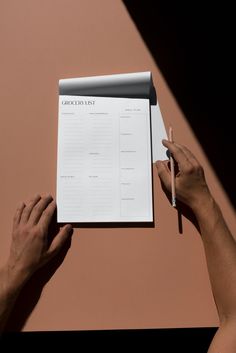 two hands holding a piece of paper with writing on it and a pen next to it