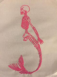 a white shirt with pink thread on it and a skeleton in the shape of a fish